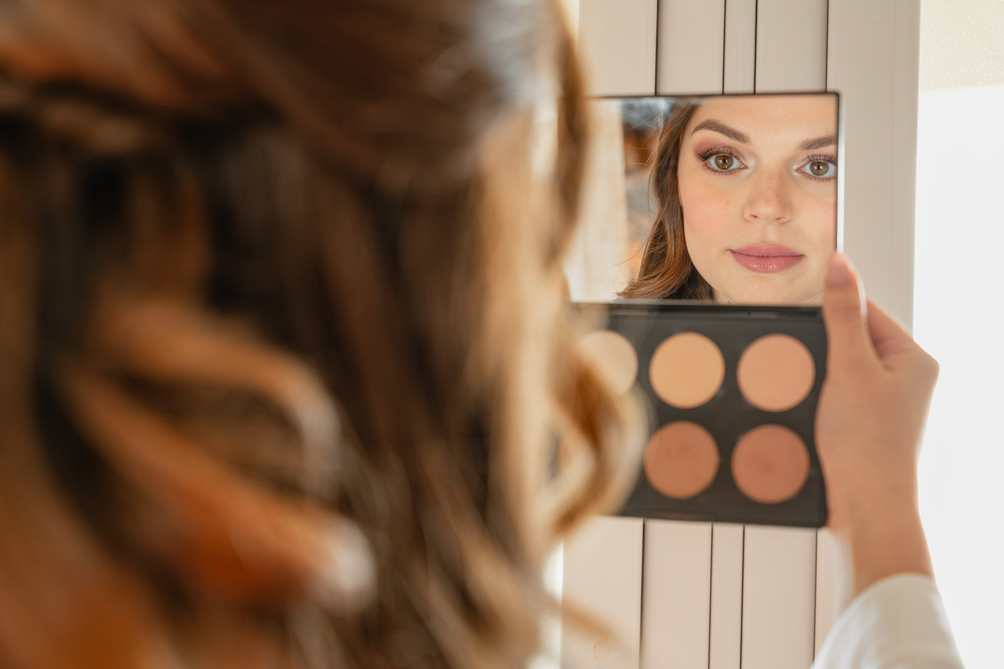 Sposa cristiana si prepara al matrimonio cristiano in Italia controllando il make-up allo specchio durante i preparativi bridal prima della cerimonia cristina.