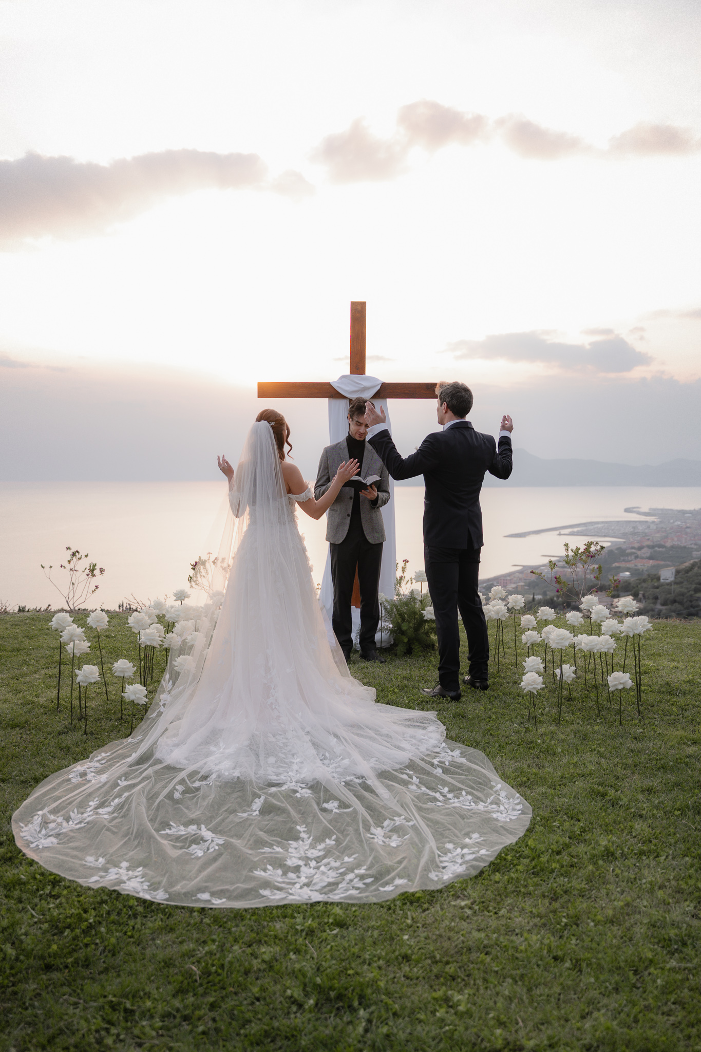 Pastore celebra la cerimonia con gli sposi durante matrimonio cristiano evangelico in Liguria davanti alla croce con vista panoramica sul mare all'Agriturismo Olivenere di Lavagna