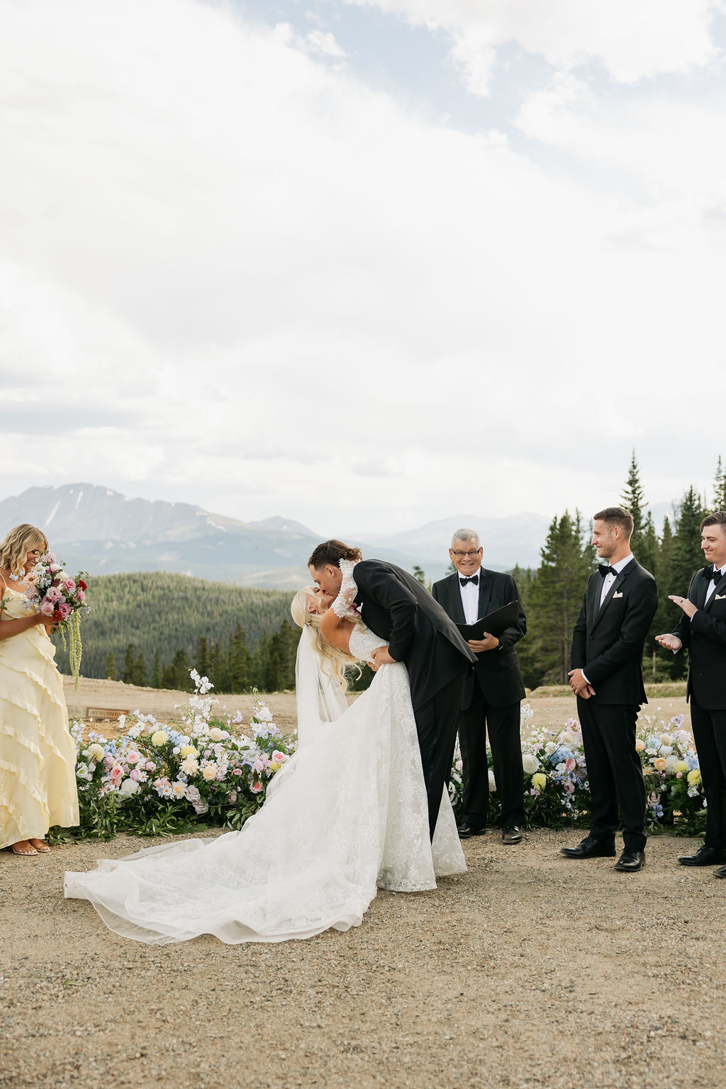 Una coppia di sposi cristiani evangelici si bacia al termine della cerimonia cristiana protestante di un matrimonio cristiano celebrato all'aperto, circondata dalla natura, famiglia, il pastore e Dio
